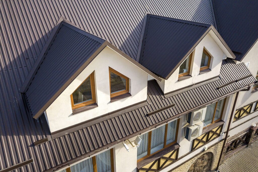 close up aerial view of building attic rooms exterior on metal shingle roof stucco walls and plastic windows 1145254175 0c436898f5574647812e891aa258bf3e scaled 1